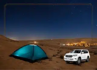 A car parked in the desert with a tent set up next to it, under the starry night sky in Dubai