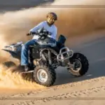 150cc quad bike riding through the desert terrain during a Desert Safari Dubai